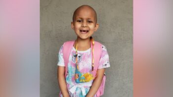 girl without hair smiles in colorful clothing